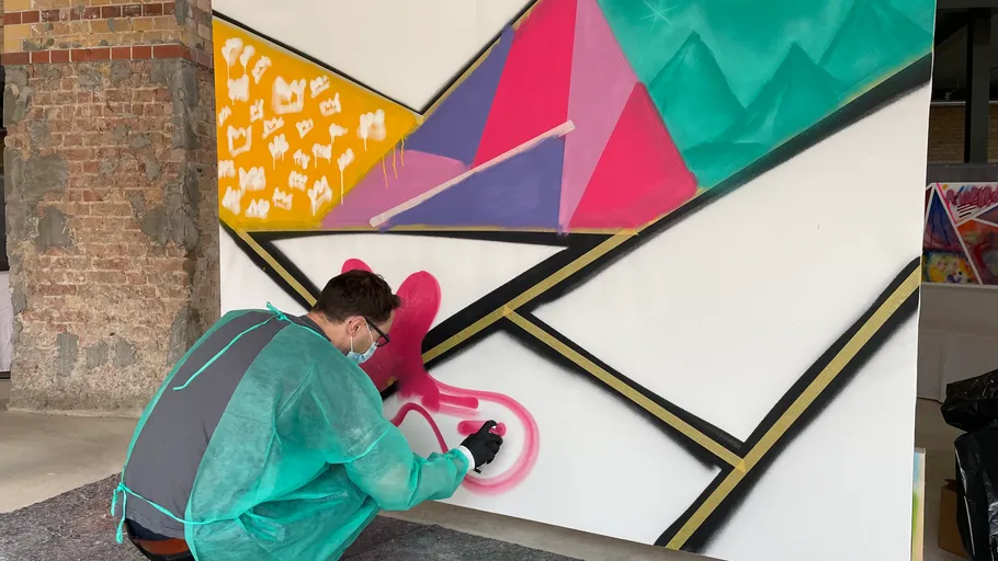 Artist spray painting colorful geometric mural.
