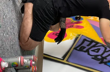 Person spray-painting artwork on floor.