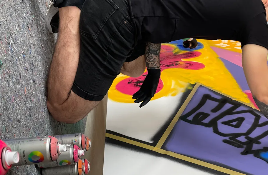 Person spray-painting artwork on floor.