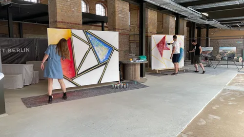 People painting abstract art on large canvases indoors.