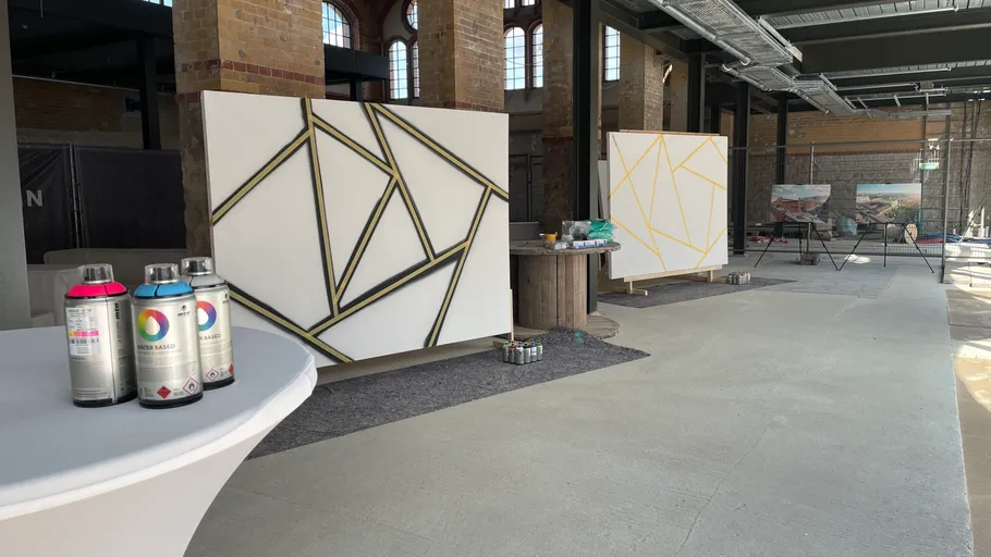 Art studio with geometric paintings and spray cans.