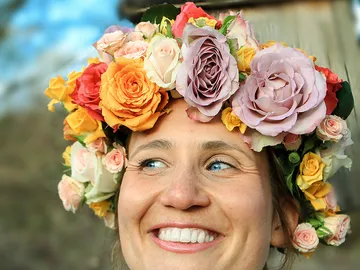 Smiling woman wearing colorful flower crown outdoors.
