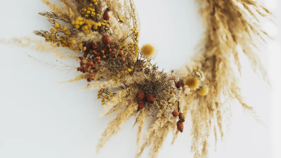 Dried floral wreath on white wall.