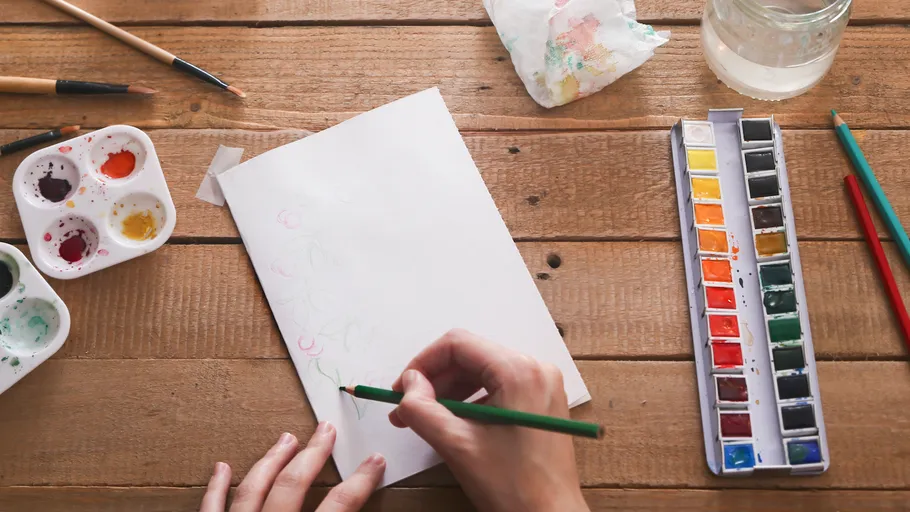 Person drawing with colored pencils on paper.