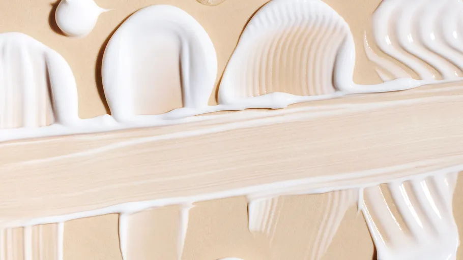 Cremetextur auf beige Oberfläche verschmiert.