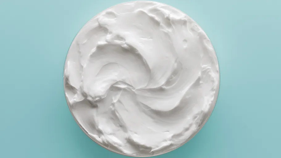 Cream swirl in a container, blue background.