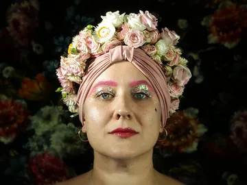 Woman with flower wreath shining against floral background.