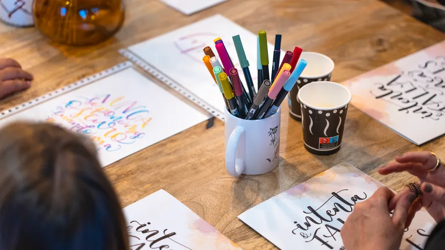 Calligraphy workshop with pens and papers on table.