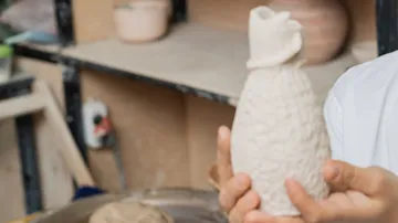 Person hält handgefertigtes Keramikstück drinnen.