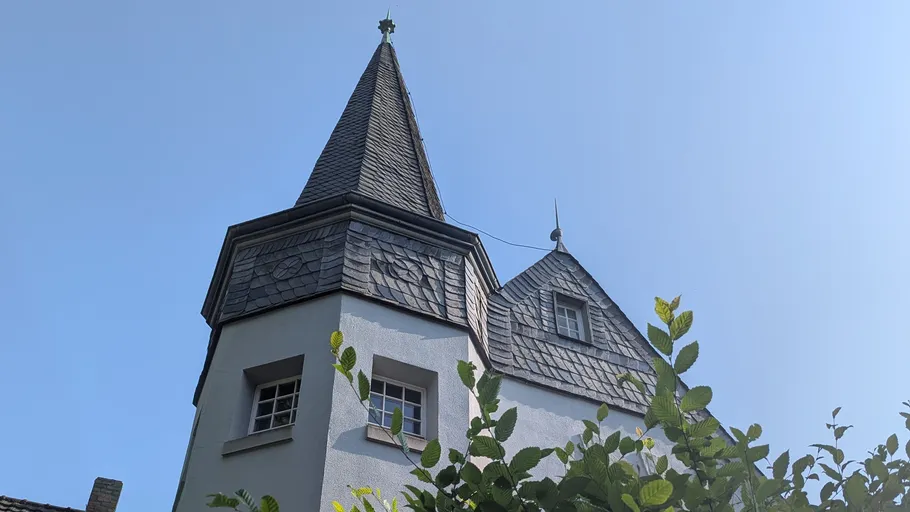 Turm mit spitzem Dach, klarer Himmel Hintergrund.