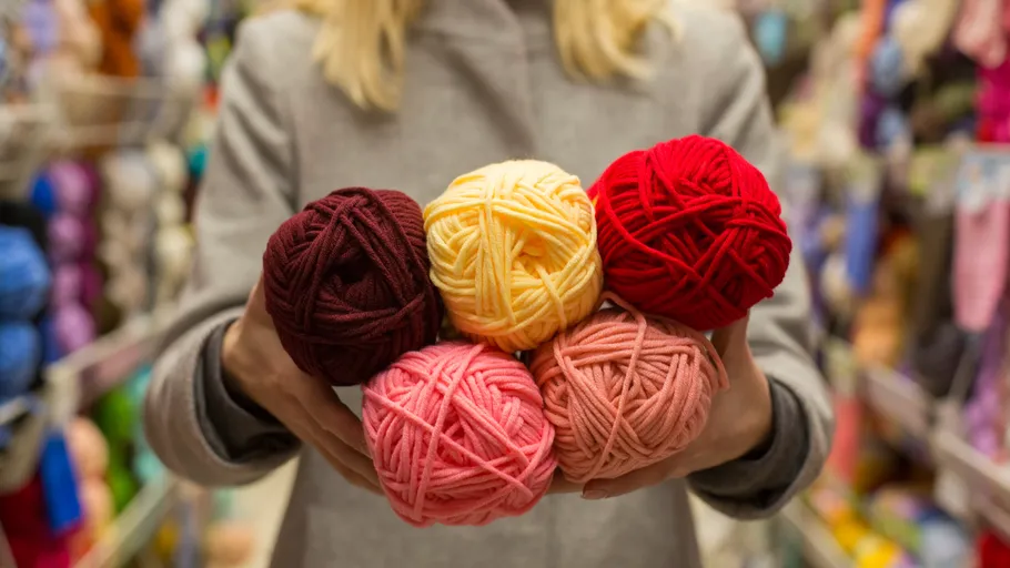 Person holding colorful yarn in a store.