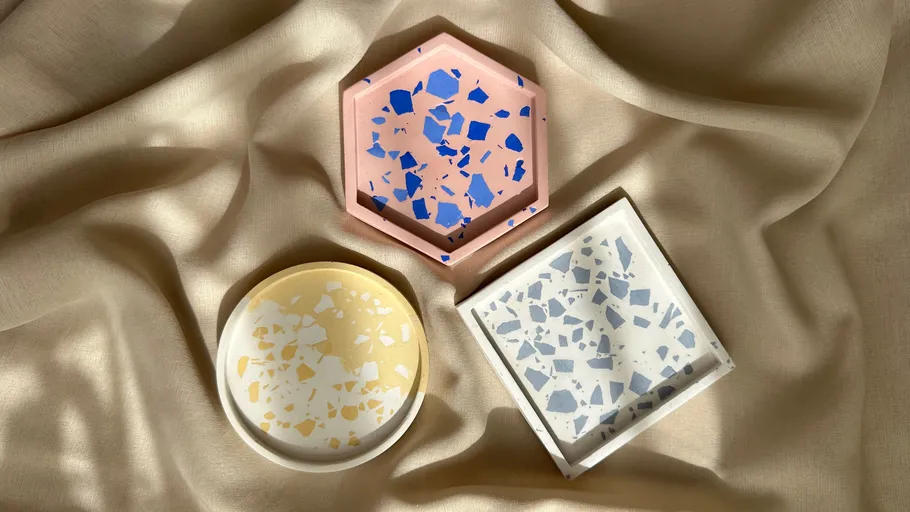 Three terrazzo coasters on beige fabric.