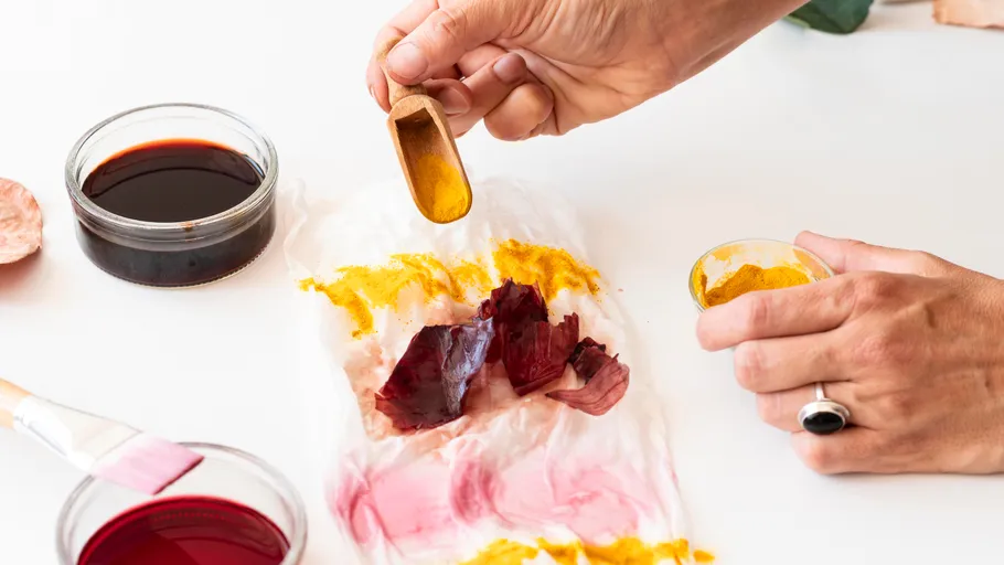Hands experimenting with natural dyes on fabric.