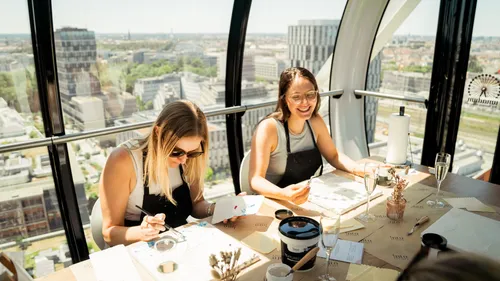Two women painting in a Ferris wheel.