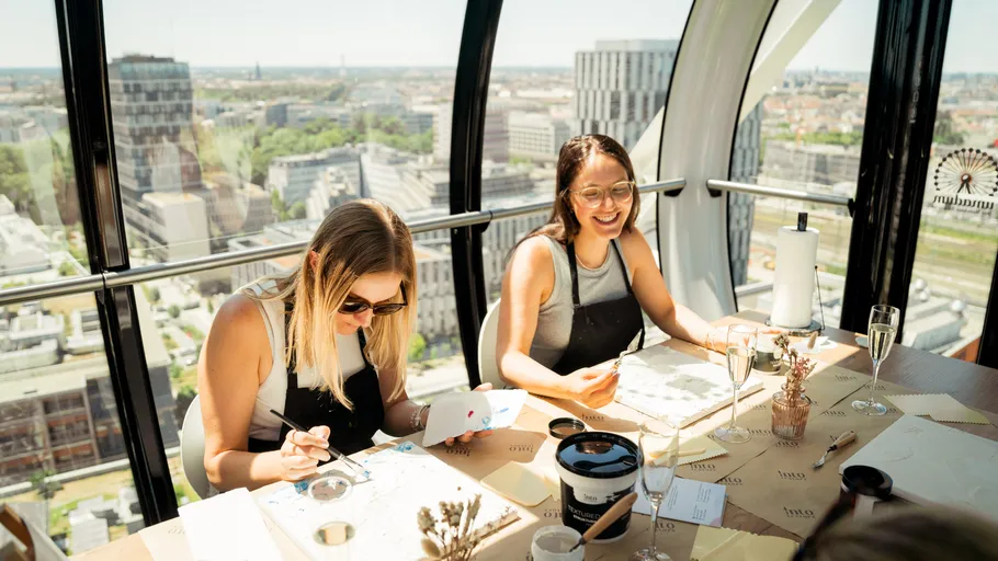 Two women painting in a Ferris wheel.