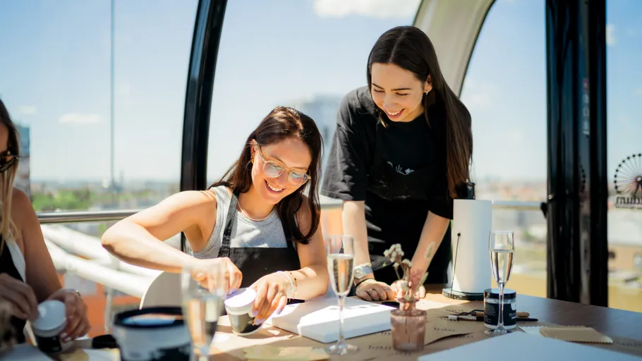 Two women crafting in glass enclosure.