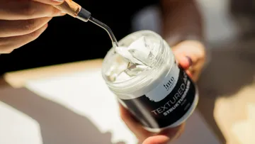 Person holding art paste with spatula.