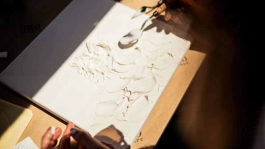Person sculpting clay on a flat surface.