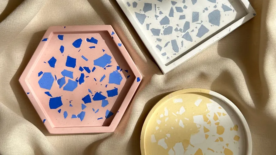 Three terrazzo coasters on beige fabric.