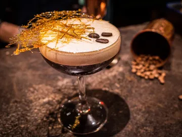 Espresso Martini with edible garnish on bar counter.