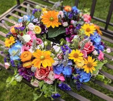 Bunte Blumenkranz liegt auf einer Bank im Garten.