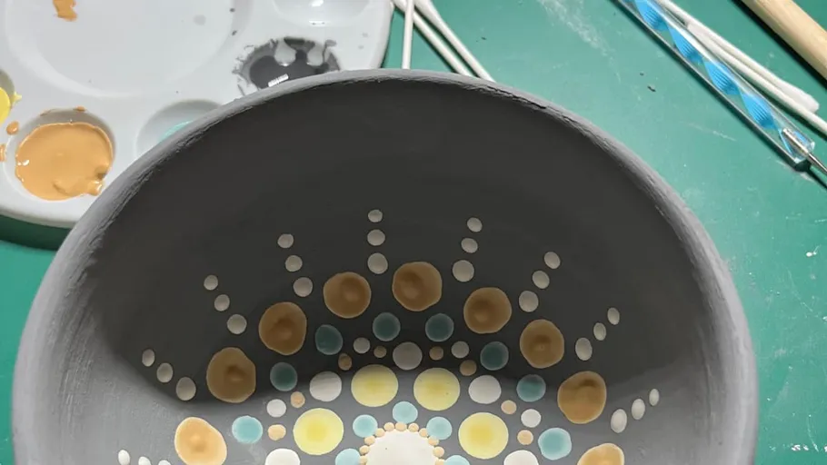 Painted bowl with dot patterns on table.