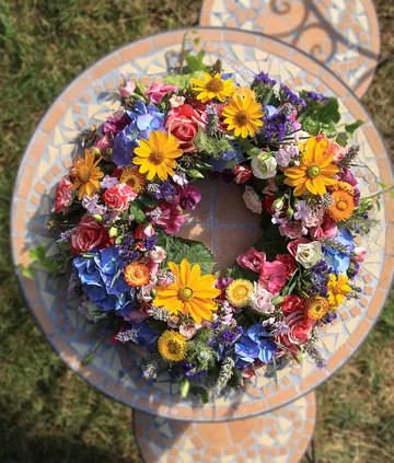 Bunter Blumenkranz liegt auf einem dekorativen Tisch.
