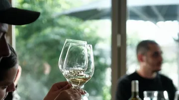 Person hält Weingläser am Tisch.
