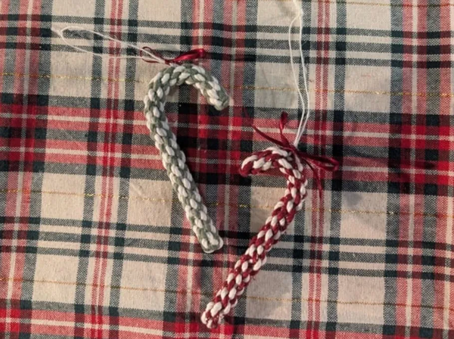 Two woven candy canes on plaid fabric.