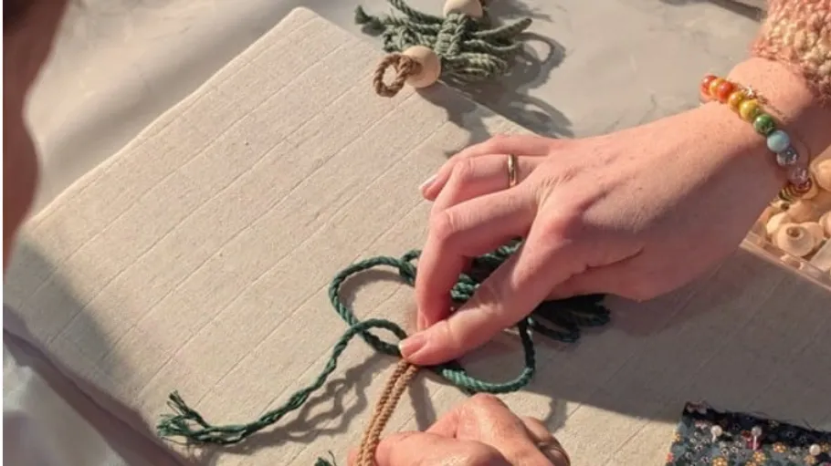 Hands knotting rope on fabric surface.