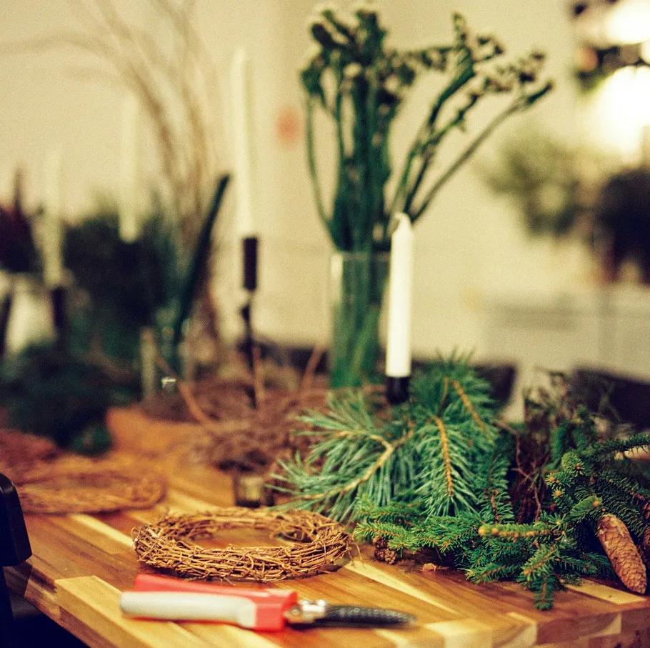 Basteltisch mit Kerzen und Kieferzweigen.