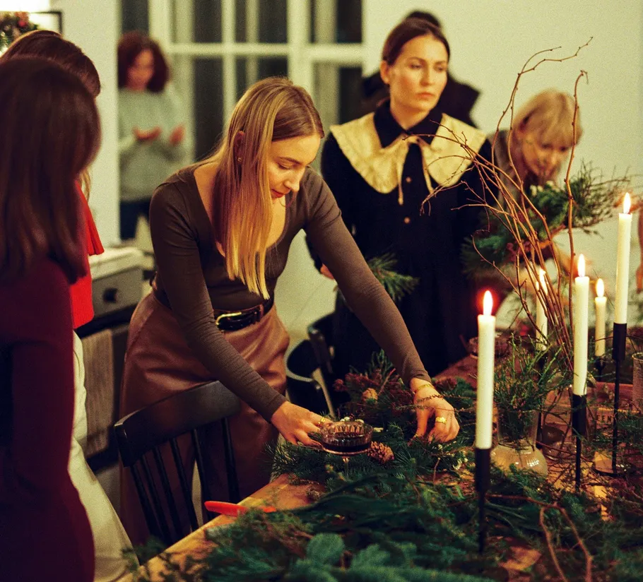 Women crafting wreaths at a decorated table.