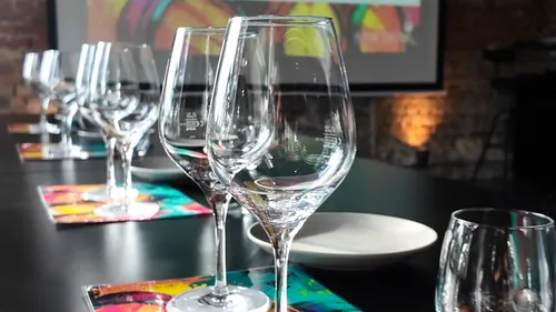 Empty wine glasses on table, projector screen behind.