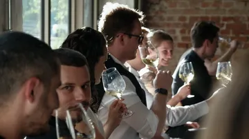 Gruppe Menschen verkostet Wein im Sonnenlicht.