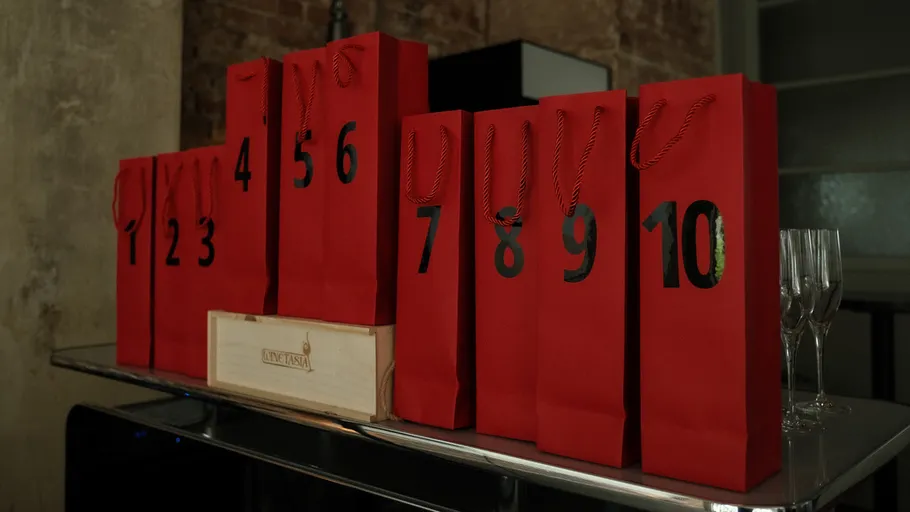 Red gift bags numbered 1 to 10 on table.