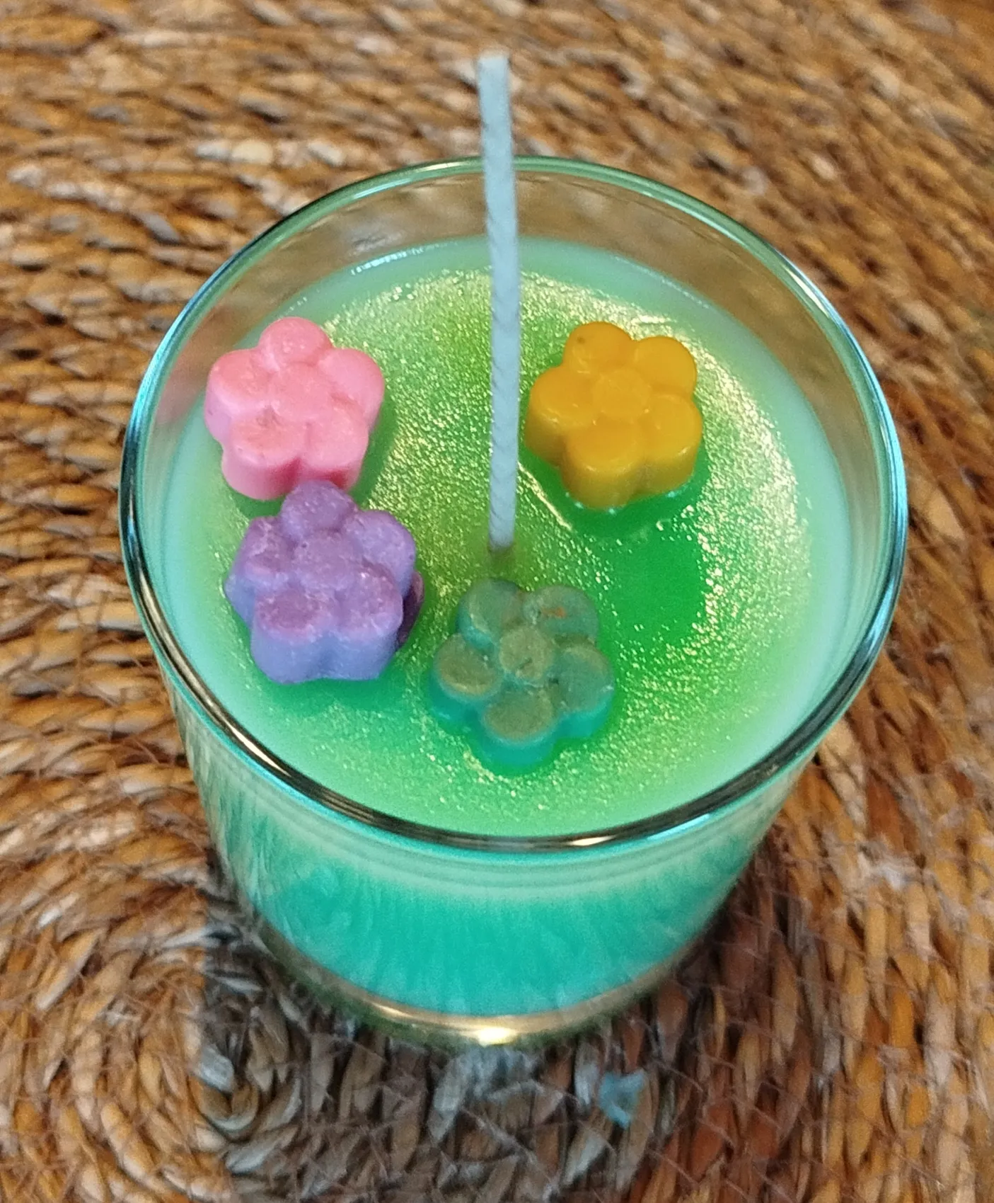 Grüne Kerze mit Blumendekorationen auf Tisch.