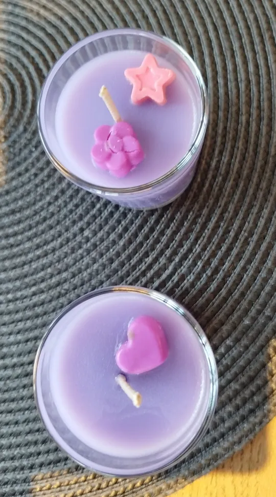 Zwei violette Kerzen mit dekorativen Formen.
