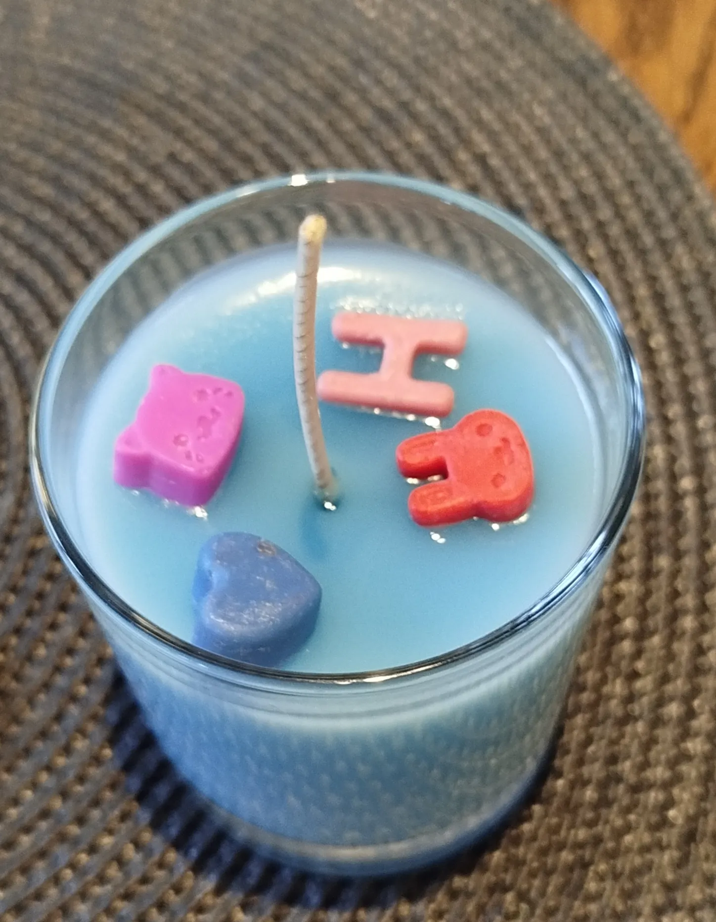 Blaue Kerze mit bunten Formen innen.