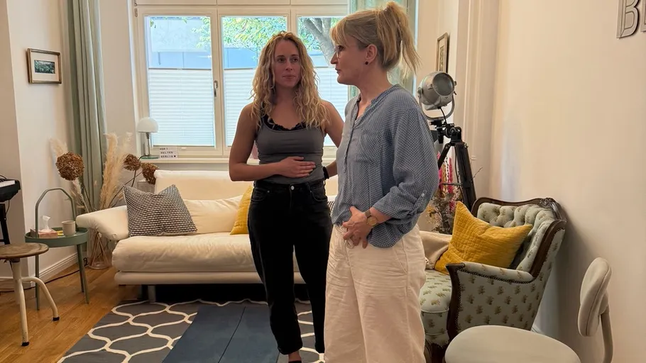 Two women talking in a living room.