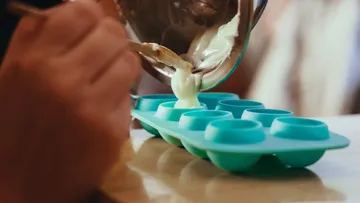 Hands pouring batter into silicone mold.