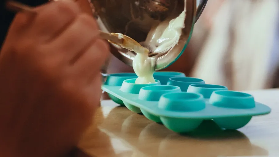 Hände gießen Teig in Silikonform.