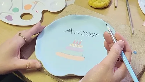 Hände bemalen Teller mit Name und Kuchen.