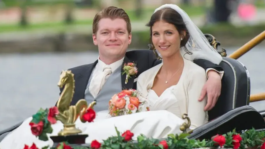 Bride and groom in flower-decorated carriage.