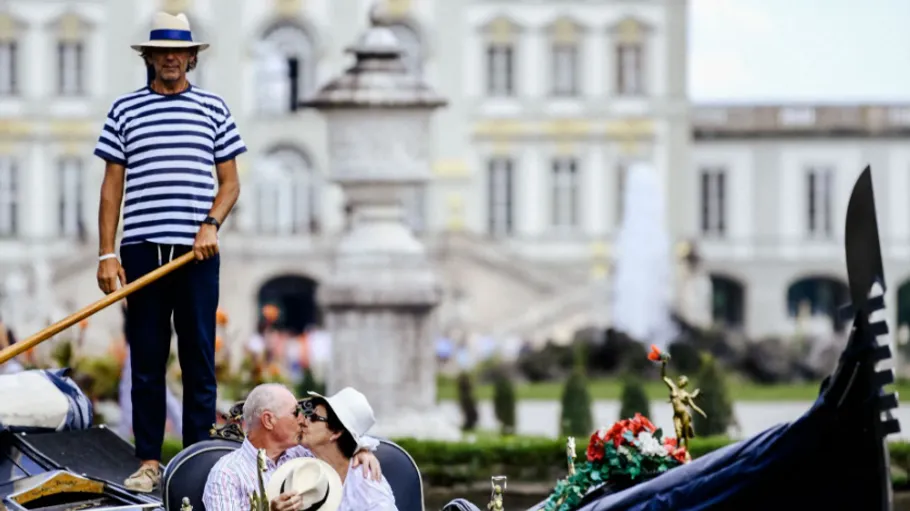 Gondolier stands as couple kisses on gondola.