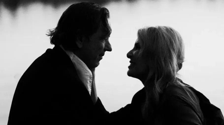 Silhouetted couple gazes at each other outdoors.