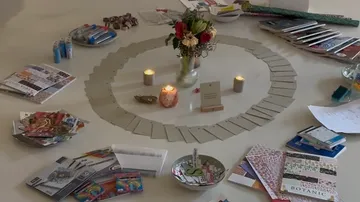 Cards, candles, flowers on a circular arrangement.
