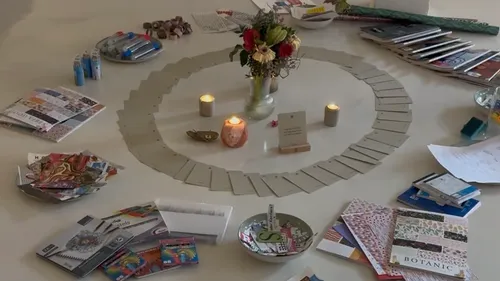 Table with candles, flowers, cards, and art supplies.