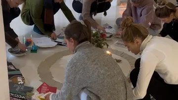 Menschen basteln gemeinsam auf rundem Bodenmatte.