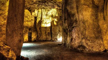 Illuminated cave with rocky walls and floor.