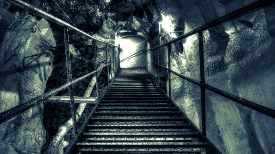 Metal stairs descending into an illuminated cave.